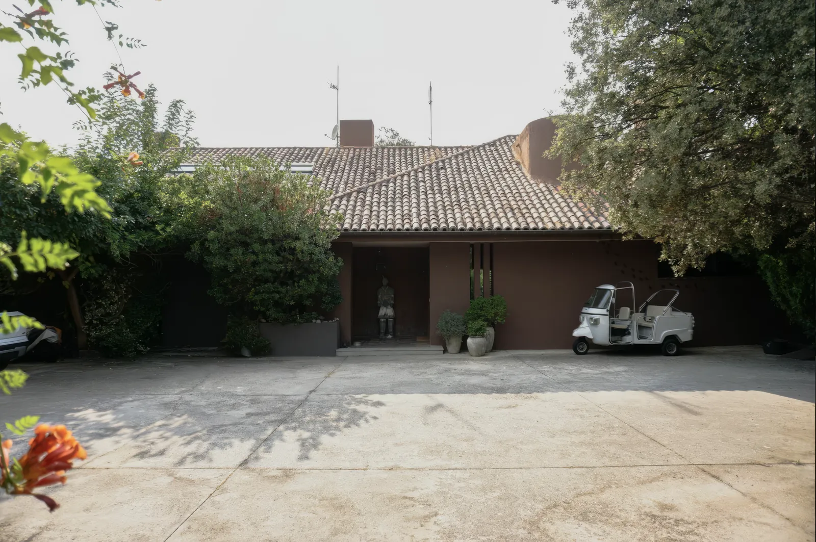 Fachada principal de la casa entre vegetación