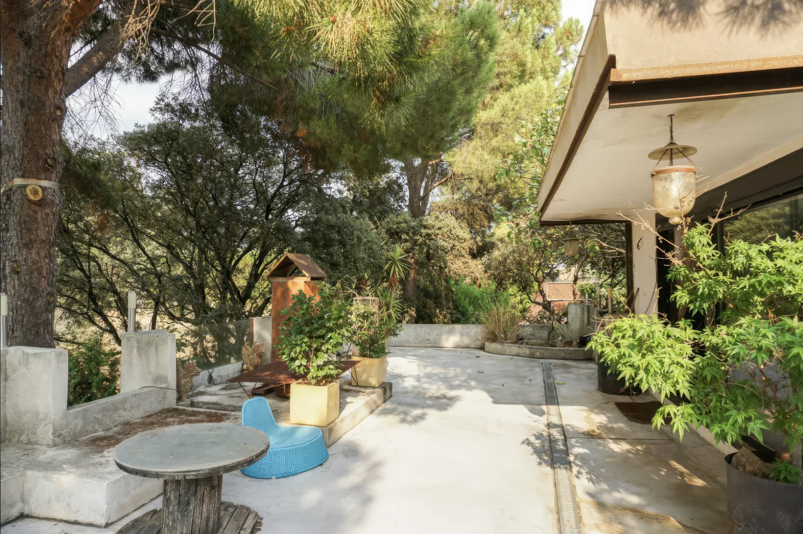 Terraza exterior con mesa de piedra y vegetación